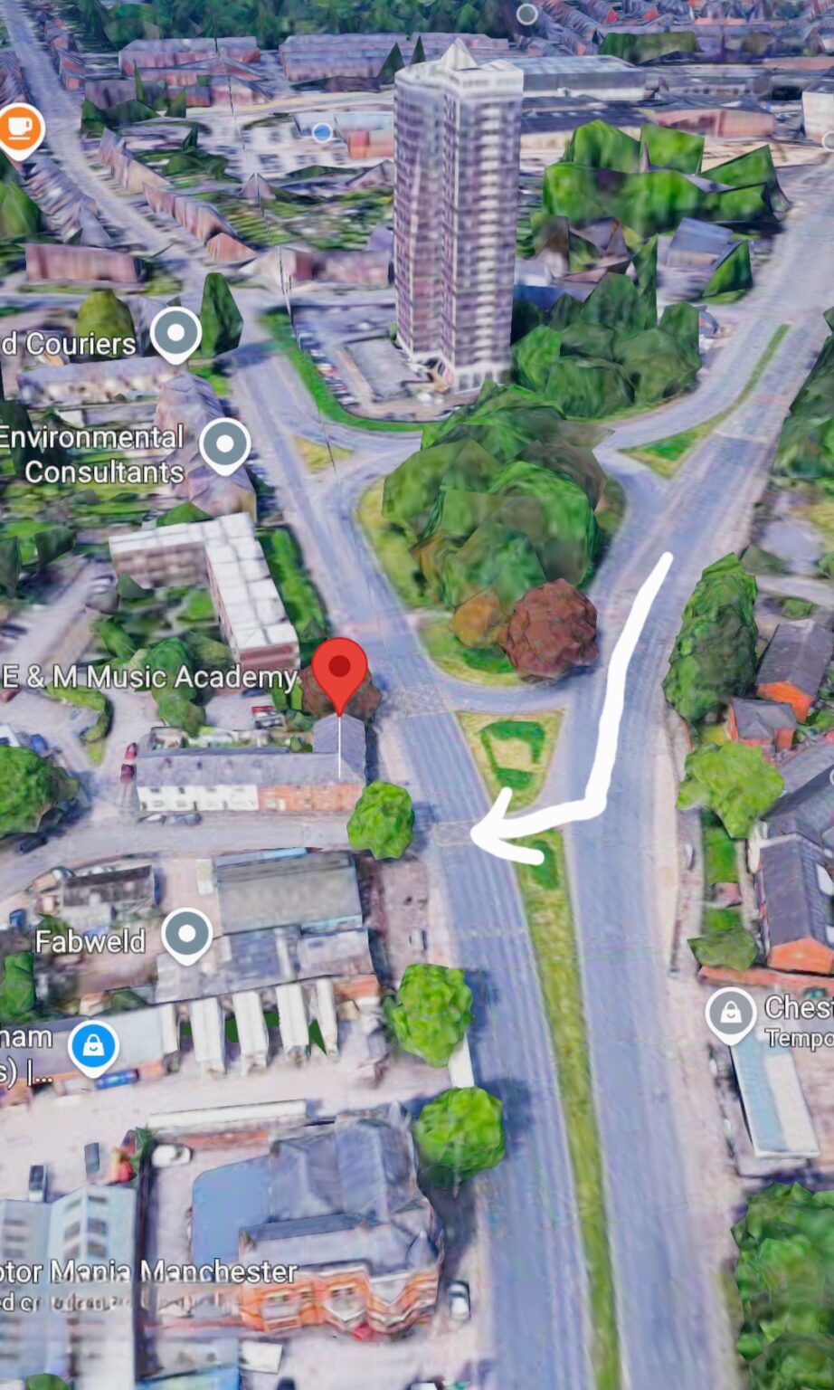 3D map view showing a red pin at E & M Music Academy, with roads and a left-turn arrow indicating navigation direction.